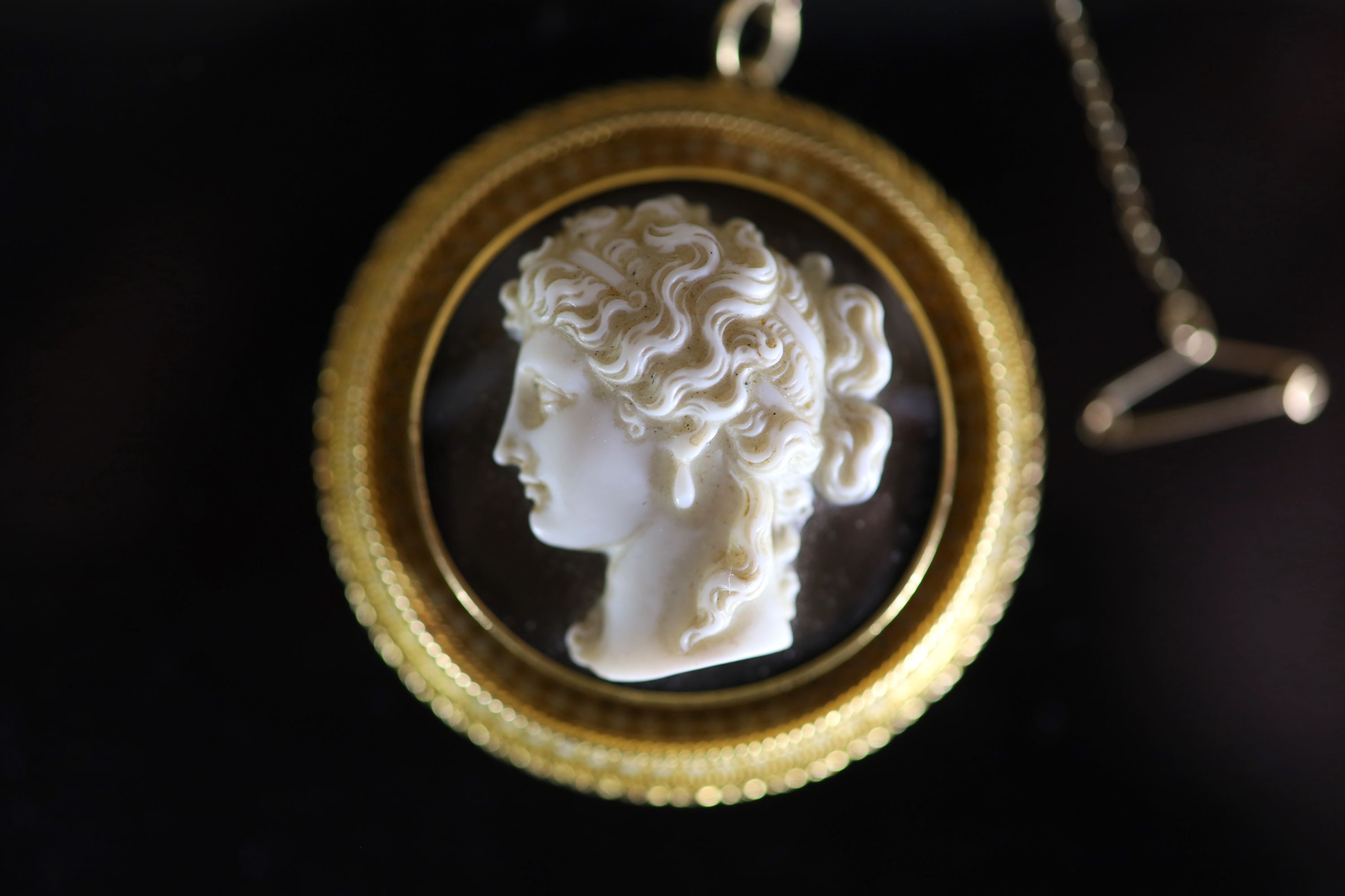 A Victorian gold and white enamel mounted agate cameo circular pendant brooch